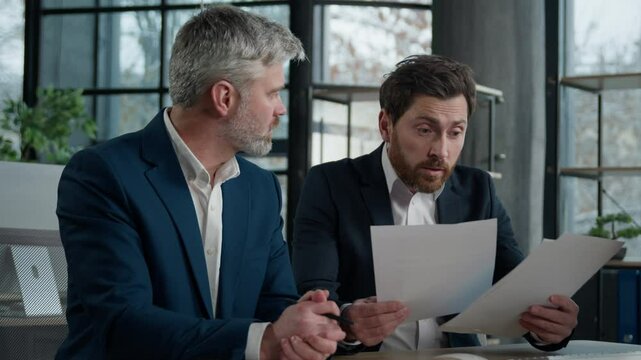 Nervous angry man boss argue scolds employee because mistake in documents financial papers Caucasian men businessmen arguing in office meeting business conflict problem mistake work failure bad result