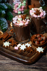 sweet hot chocolate with marshmallows in glass mugs on wooden background, vertical