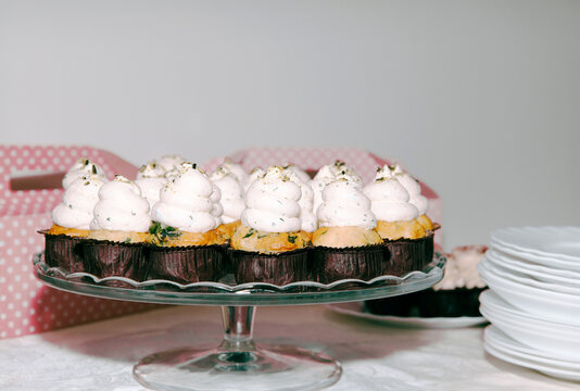 Delicious vanilla cupcakes with creamy frosting on glass stand at party