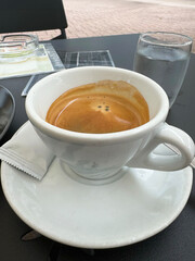 Classic espresso on outdoor café table setting with glass of water