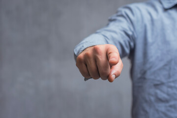 Concept of pointing finger. Close-up of a man in a shirt pointing his finger forward against a concrete wall.