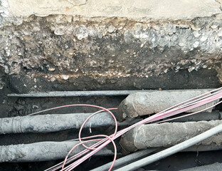 Underground utility maintenance showing cables and pipes in construction site excavation