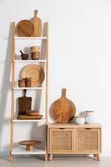 Storage stand and cabinet with kitchenware near white wall indoors
