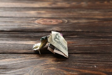 One crumpled dollar banknote on wooden table, closeup