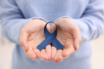 Fototapeta premium Woman with dark blue ribbon on light background, closeup. Arthritis disease and colon cancer awareness