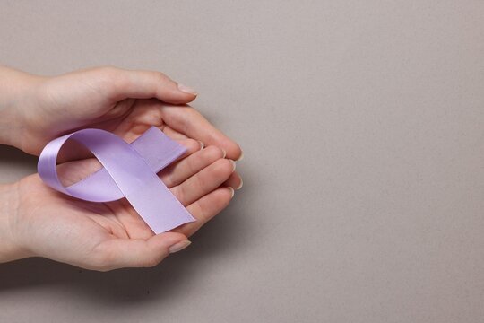 Woman with violet ribbon on grey background, top view with space for text. Alzheimer disease, epilepsy and pancreas cancer awareness