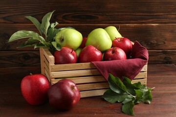 Ripe red and green apples in crate on wooden table