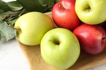 Ripe apples and green leaves on white table, closeup