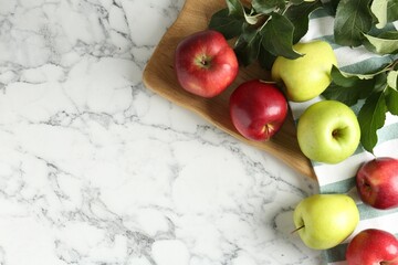 Ripe apples and green leaves on white marble table, top view. Space for text