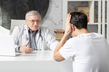 Young man visiting Senior male doctor in modern clinic	
