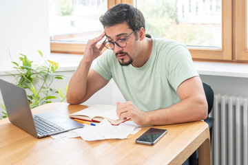 Close up of unhappy man sitting at the table, stressed and confused by calculate expense from invoice or bills, have no money to pay mortgage or loan. High prices and spending money concept