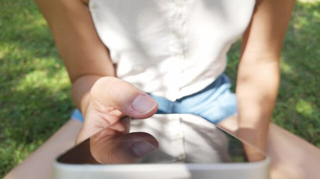Anonymous woman sitting on grass using her touchscreen phone