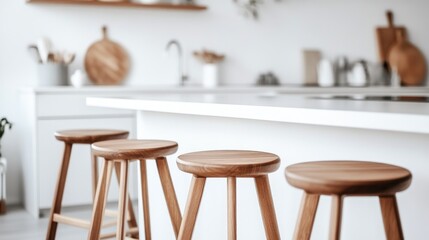 A modern kitchen with wooden stools around a white countertop.