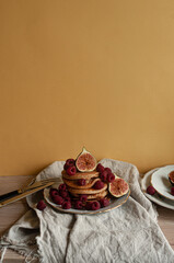 Delicious whole wheat healthy pancakes with raspberry, figues and copy space on the table with linen cloth background lifestyle