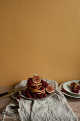 Delicious whole wheat healthy pancakes with raspberry, figues and copy space on the table with linen cloth background lifestyle