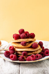 Delicious whole wheat healthy pancakes with raspberry, fork and knife styling natural light and copy space on the table with linen cloth background lifestyle