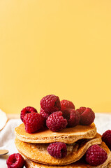Delicious whole wheat healthy pancakes with raspberry, fork and knife styling natural light and copy space on the table with linen cloth background lifestyle