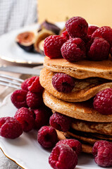 Delicious whole wheat healthy pancakes with raspberry, fork and knife styling natural light and copy space on the table with linen cloth background lifestyle