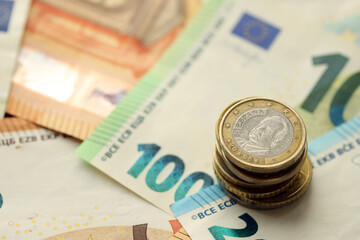 One euro coin lies on huge amount of different euro dollars banknotes