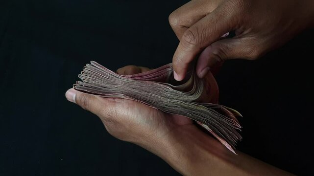 hands counting millions of rupiah