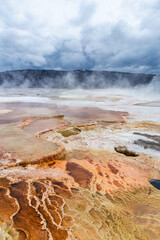Stunning Geothermal Landscape in Yellowstone National Park, Wyoming Featuring Vibrant Thermal Pools and Steaming Geysers Under Moody Clouds