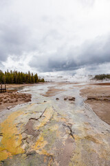 Scenic View of Geothermal Activity in Yellowstone National Park, Wyoming, Featuring Colorful Hot Springs and Steaming Geysers Amidst a Dramatic Cloudy Sky