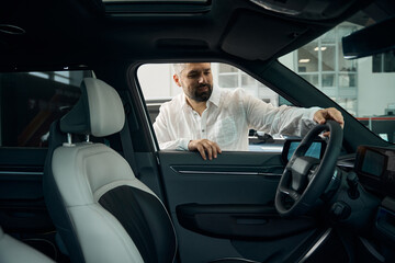 Bearded young man in a standing near the new car