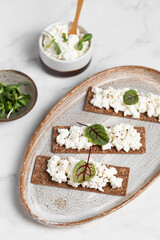 Homemade crispy toasts with ricotta, cottage cheese and herbs, microgreens, healthy eating, food for athletes