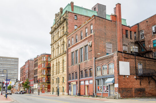 Traditional American tall brick apartment buildings with shops on ground level along a street in a historic district on a cloudy autumn day