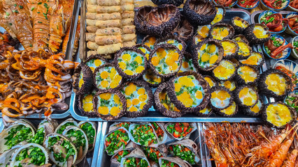 Vibrant and diverse street food stall overflowing with variety of grilled and cooked dishes on Cho...