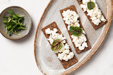 Homemade crispy toasts with ricotta, cottage cheese and herbs, 
microgreens, healthy eating, food for athletes