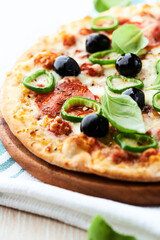 Pizza with salami, jalapeno pepper and black olives. Home made food. Concept for a tasty and hearty meal. Close up.	