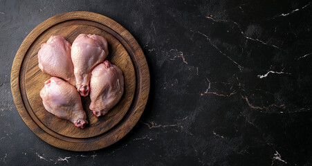 Raw chicken on a wooden board, isolated on a dark background. Top view. Space for text or copy space. 