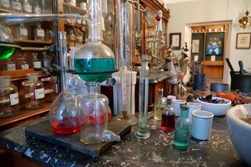 Chemistry flasks with liquids, herbs of medicinal plants in an old pharmacy
