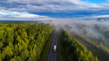 A truck and cars are driving along a beautiful road