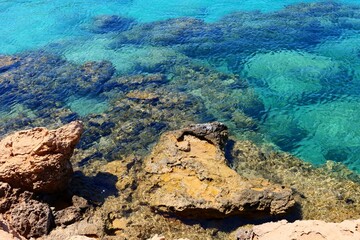 Rocky romantic vivid shoreline with stones, calm clear paradise ocean. Turquoise sea, vacation destination. Paradise bay with clear water, travel photography.