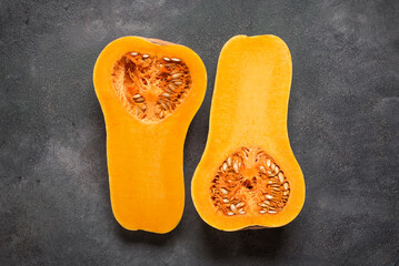 Halves of raw Butternut pumpkin on dark grunge background, top view, flat lay, copy space