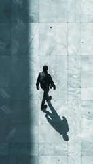 A man walks away from the camera, his silhouette cast long and stark against the tiled ground.