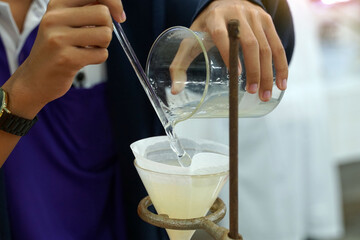 Experiment to separate mixed substances by pouring substances into a separator funnel through...