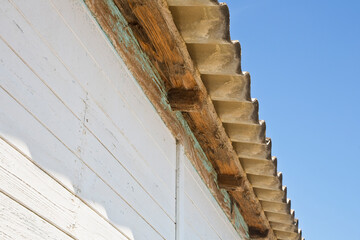 Old aged dangerous roof made of prefabricated corrugated panels with wooden structure agains a...