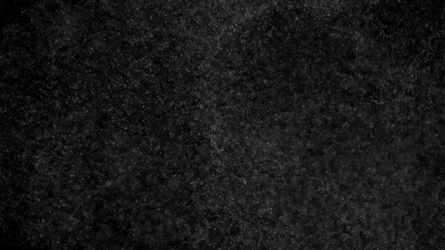 Swirling Small Particles. Small white particles flow in the air on a black background. Slow Motion