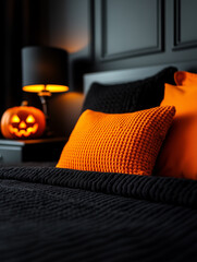 Orange and black pillows and blanket decorating a bed with a jack o'lantern on a nightstand in a dark bedroom for halloween