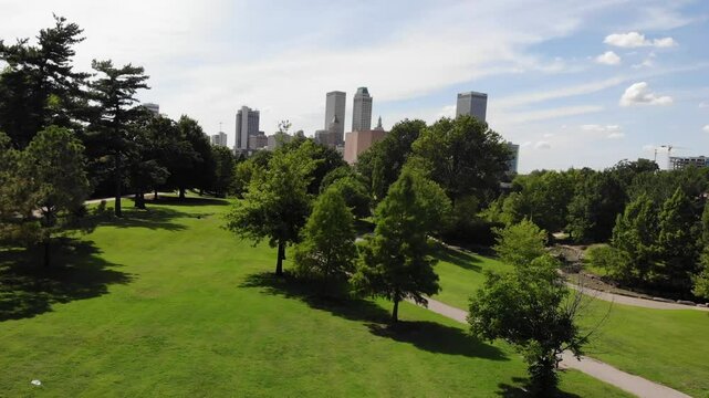 Tulsa, OK USA - August 30, 2022: Aerial drone video of downtown Tulsa skyline appearing over urban park area.
