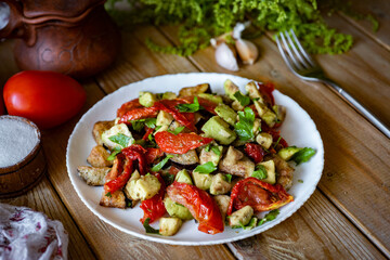 Salad with dried tomatoes, avocado and eggplant in a plate on a wooden table. Salad with dried tomatoes and vegetables for lunch. Close-up