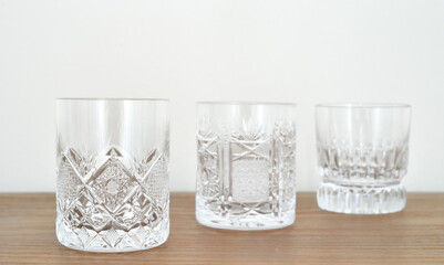 Different types of elegant empty crystal glasses on the brown wooden table. Close-up. Copy space. Selective focus.