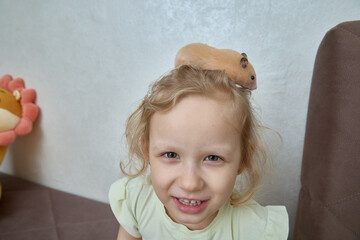 A Dzungarian hamster on a child's head in close-up. Caring and friendship for a pet