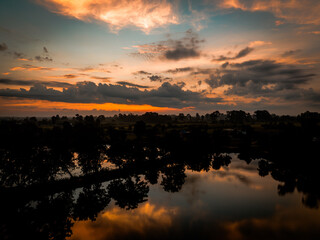 Serene sunset over a tranquil lake surrounded by lush fields in the countryside