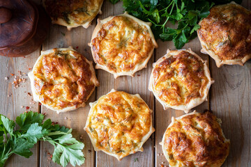 Casserole with cheese on a wooden table. Small open cheese pies. View from above. Close-up