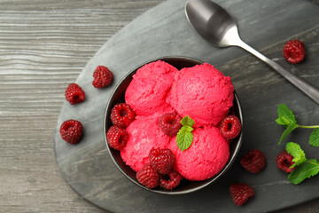Delicious raspberry sorbet in bowl, fresh berries, mint and spoon on wooden table, top view