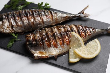 Delicious grilled mackerel and lemon on white table, closeup